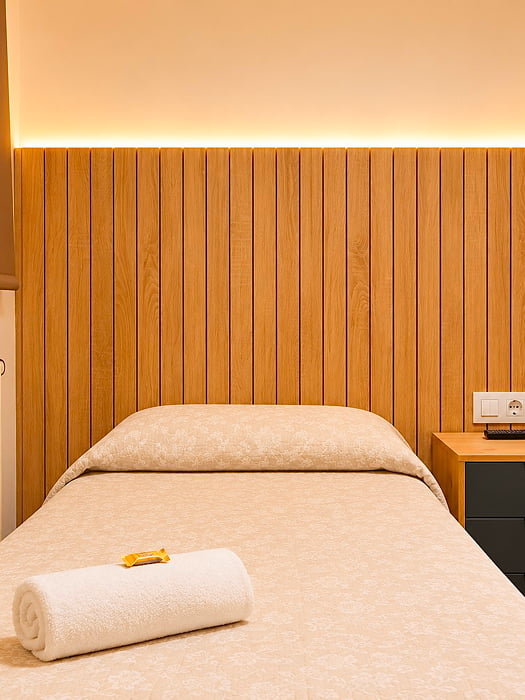Habitación individual con cama cómoda y  pared de madera