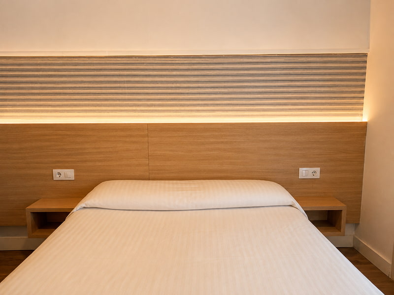 Cabecero iluminado con camas individuales y acabados en madera clara
