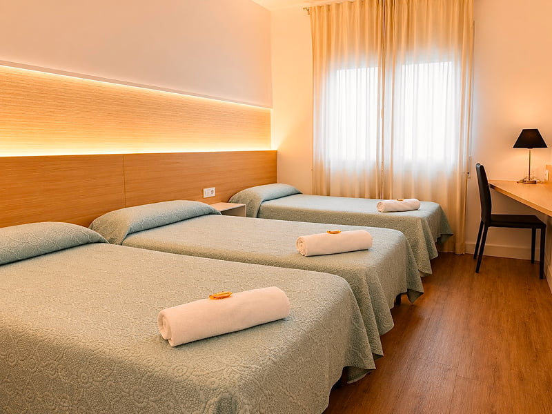 Cama individual con iluminación ambiental y detalles en madera clara